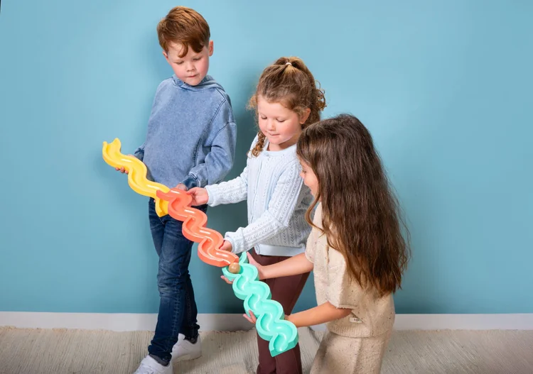 Troje dzieci wspólnie prowadzi kulkę po torach Pass & Play BS Toys